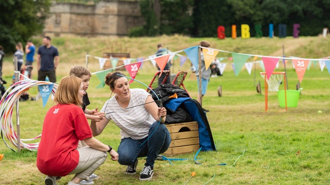 Families playing soft archery on 'Summer of Play' activities field at Gibside